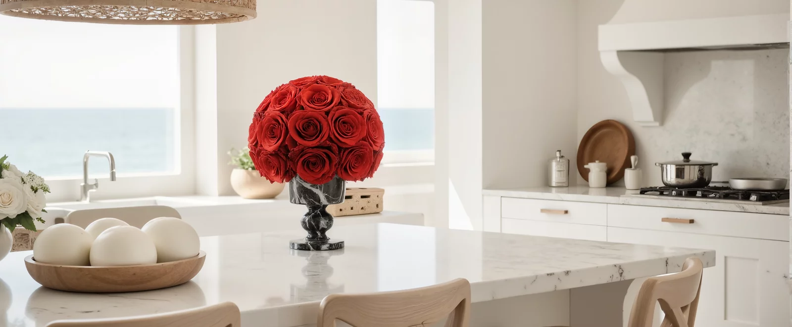 Coastal kitchen with ocean view, white island, and red rose bouquet